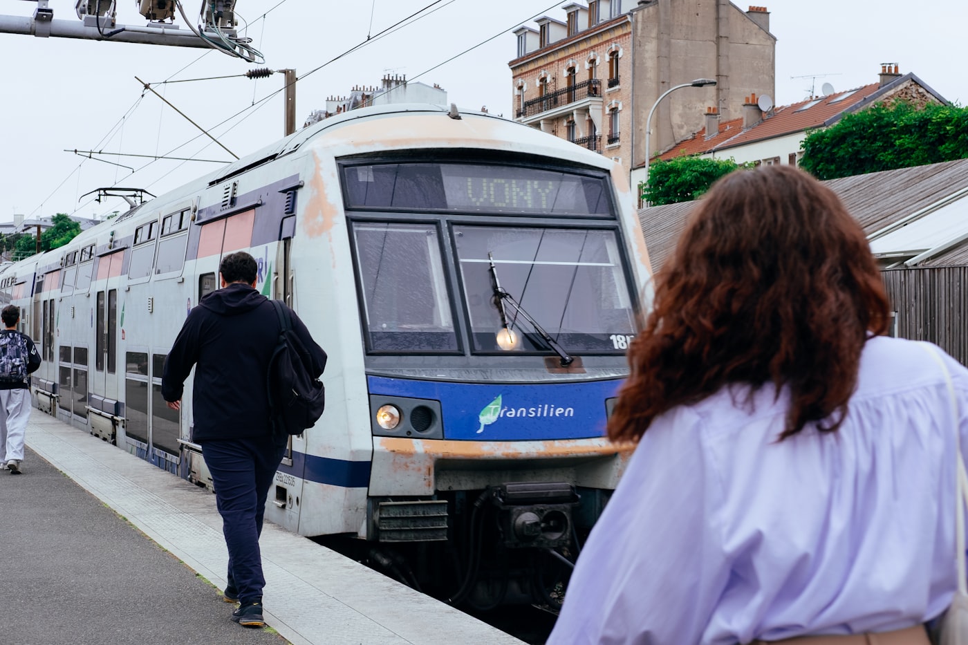 Pendler auf dem Bahnsteig neben einem einfahrenden Zug